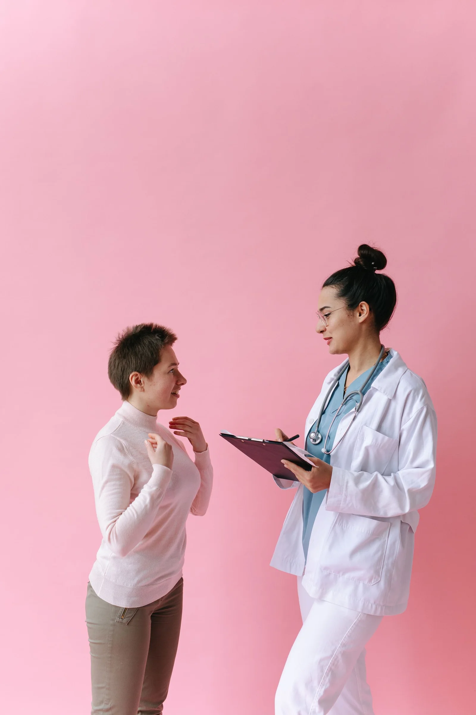 Médica conversa con una paciente y revisa información clínica.