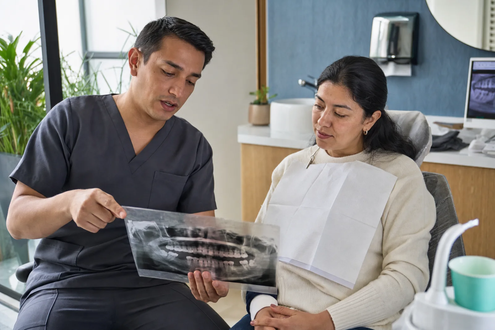 Odontólogo mexicano explica una radiografía panorámica a una paciente antes de un procedimiento oral.